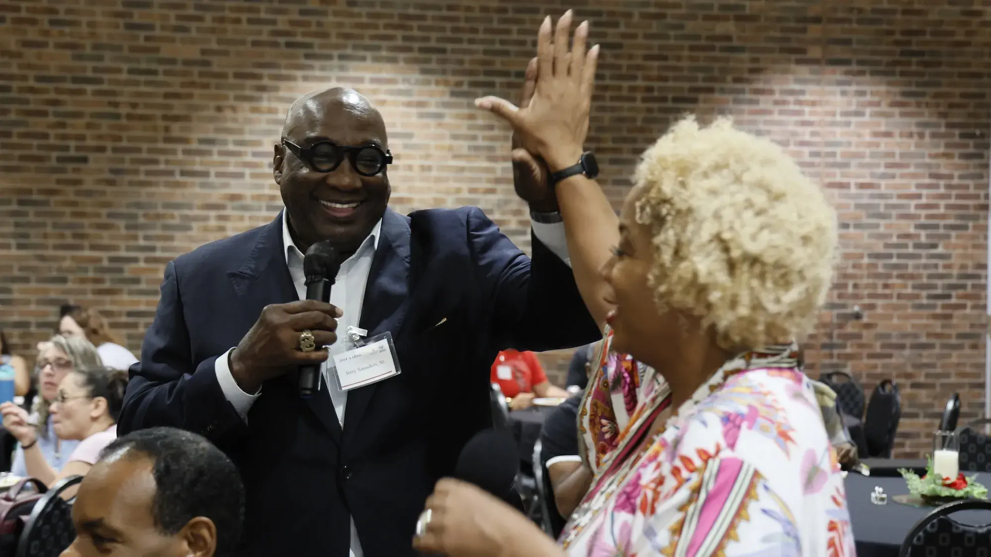Jerry Saunders Sr. giving an attendee a high five while speaking at the 2024 AABHC
