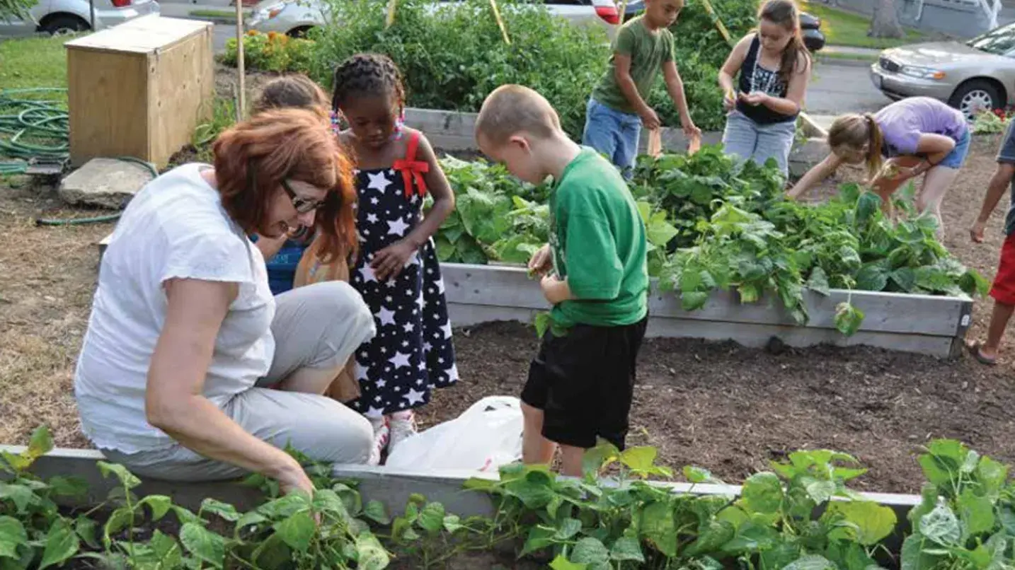 Female teacher educating a group of children in a garden