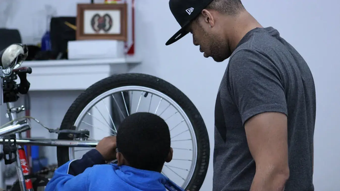 Adult man showing a child how to repair their bicycle