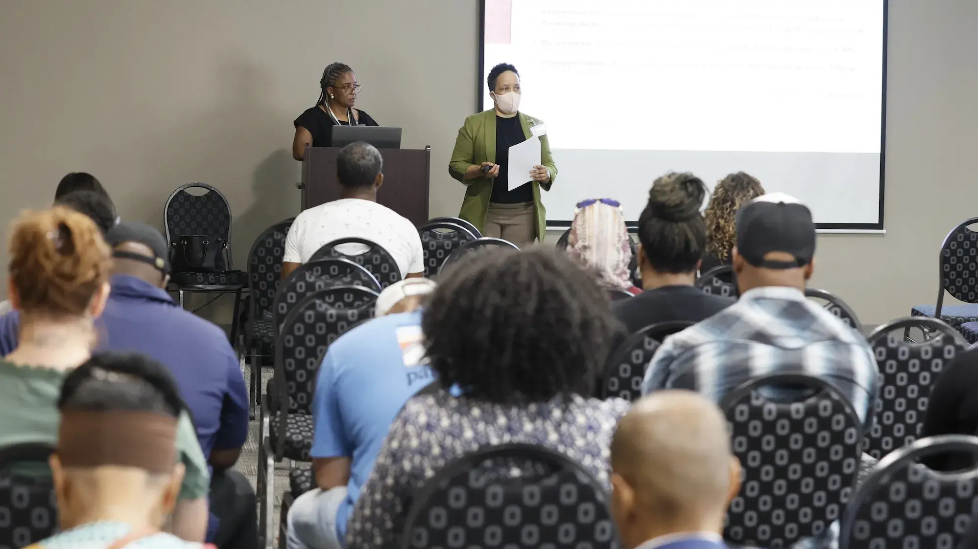 Two people giving a presentation to a full room at AABHC